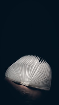 An open book with layered pages glowing softly against a dark background