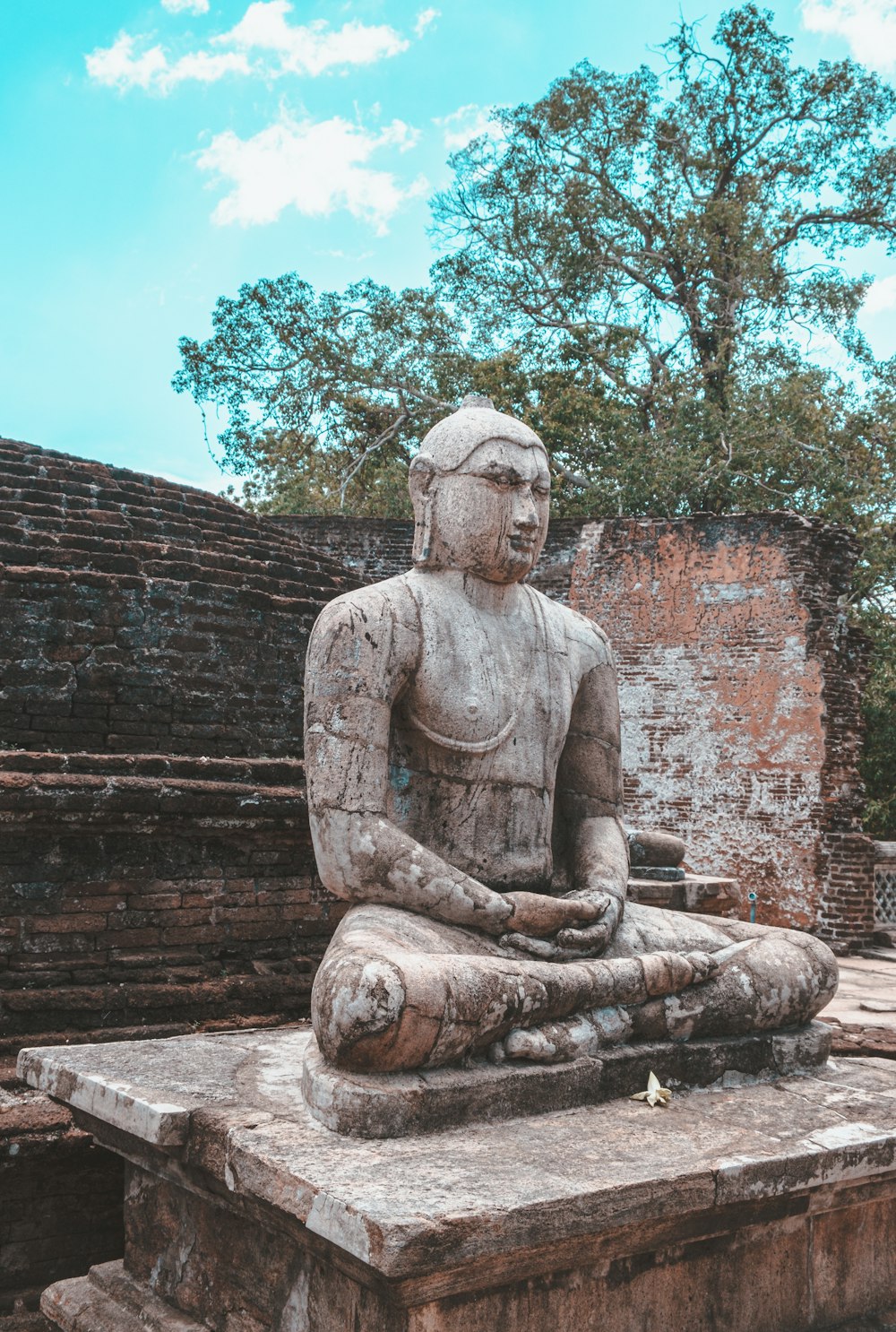 brown concrete statue near brown brick wall during daytime