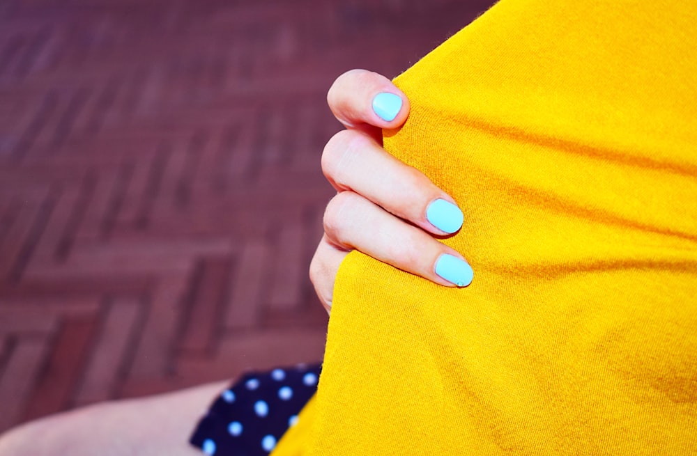person with blue manicure holding orange textile