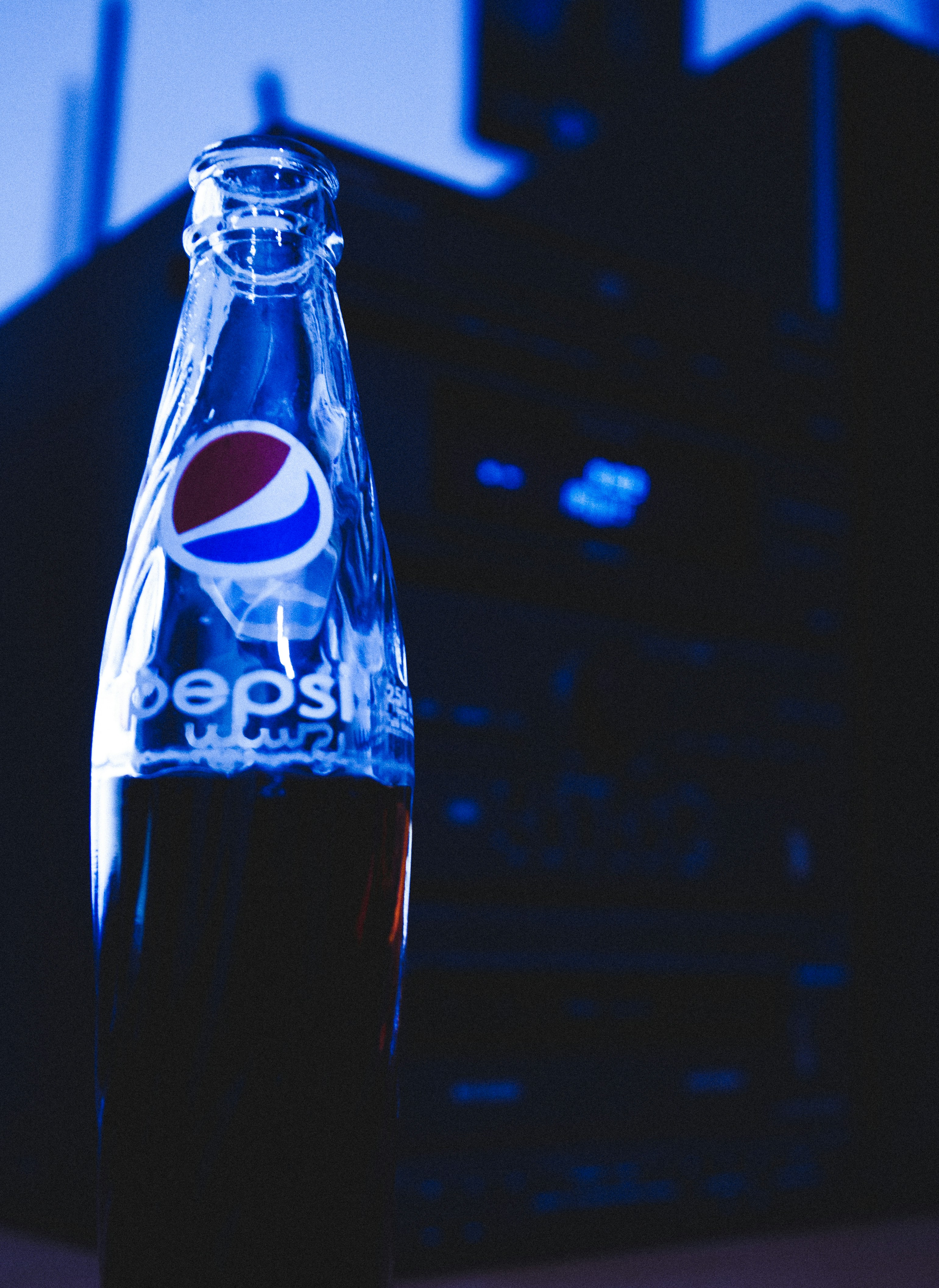 Pepsi bottles illuminated with warm golden Ramadan lighting against deep dark background