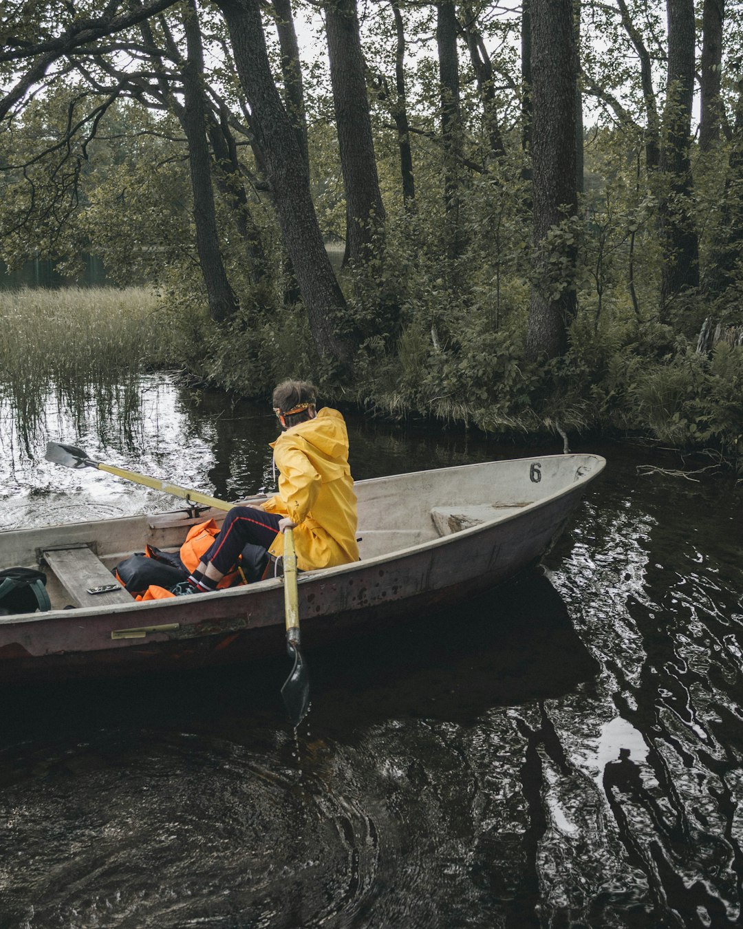 man in yellow jacket riding on brown boat on river during daytime