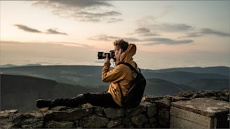 man in brown jacket taking photo of mountain during daytime