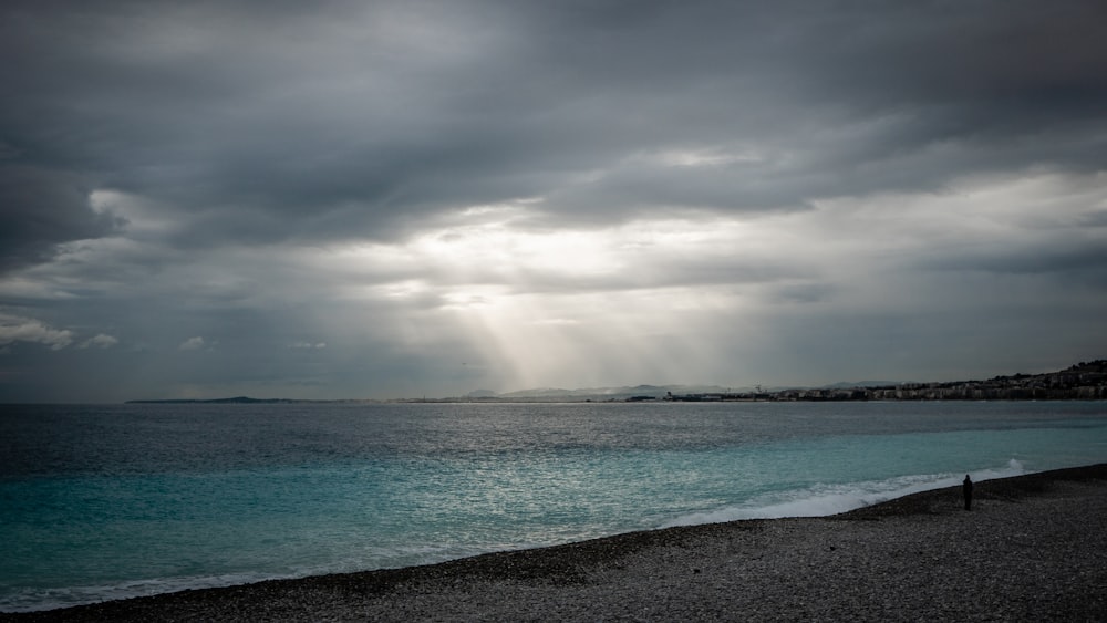 sea waves crashing on shore under cloudy sky during daytime