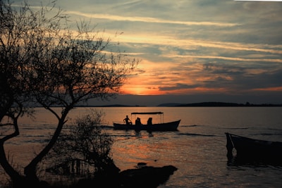 Sunset over the lake with silhouettes of people enjoying a boat ride.