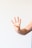 A hand with light skin tones is raised against a plain white background, with four fingers extended and the thumb tucked in. The hand appears to be making a gesture similar to the number four. A ring is worn on one of the fingers.