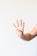 A hand with light skin tones is raised against a plain white background, with four fingers extended and the thumb tucked in. The hand appears to be making a gesture similar to the number four. A ring is worn on one of the fingers.