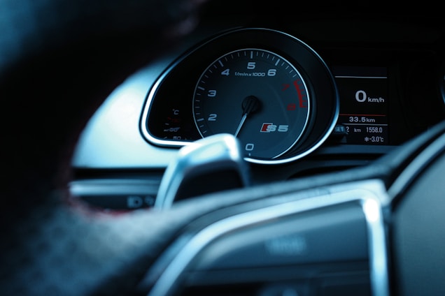 A close-up view of a car's dashboard featuring a speedometer and tachometer. The tachometer is marked with the 'S5' logo, indicating a high-performance model. The speedometer reads zero kilometers per hour and the digital display shows trip details and the exterior temperature.