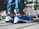 A smiling woman in casual clothes showing off her bright Zorqavia sneakers outdoors.