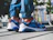 A smiling woman in casual clothes showing off her bright Zorqavia sneakers outdoors.