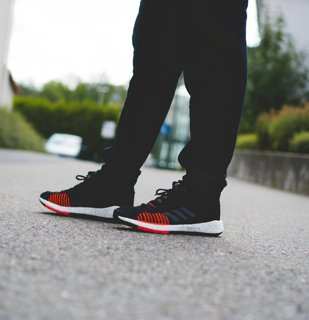 person in black pants and red and white nike sneakers