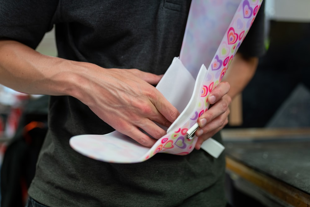 person holding white and pink floral textile