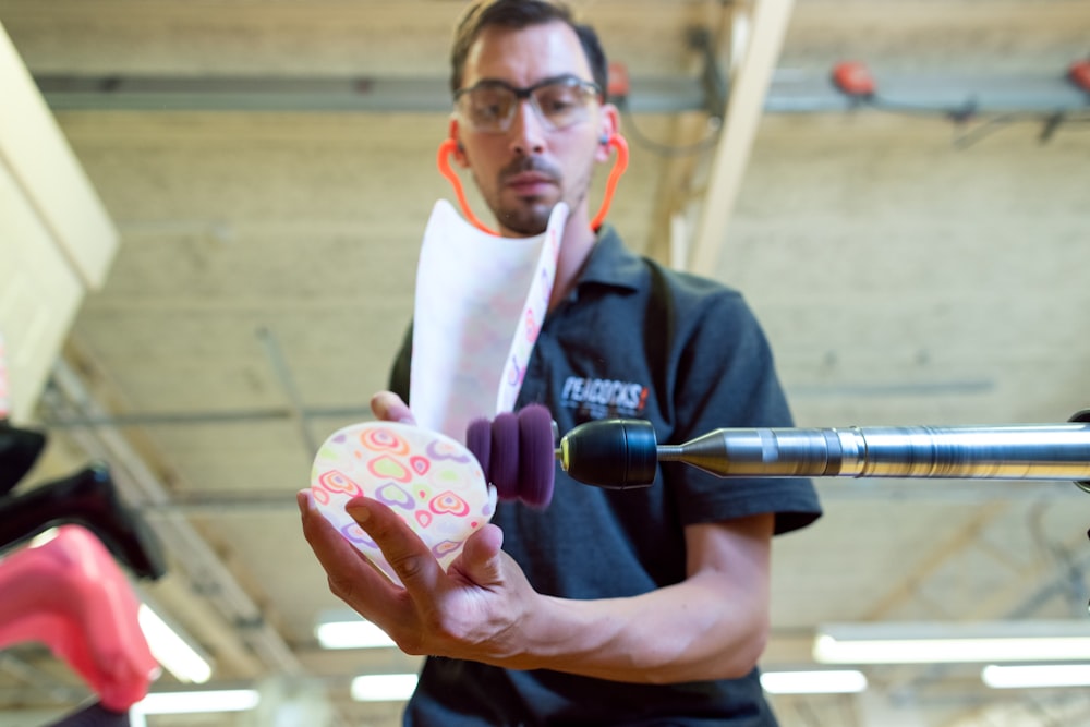 hombre en polo negro sosteniendo una taza de cerámica floral rosa y blanca