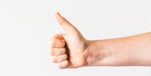 persons right hand doing thumbs up