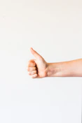 persons right hand doing thumbs up