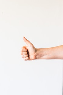 persons right hand doing thumbs up