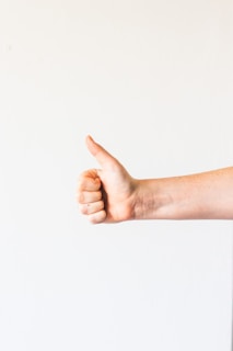 persons right hand doing thumbs up