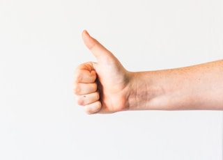 persons right hand doing thumbs up