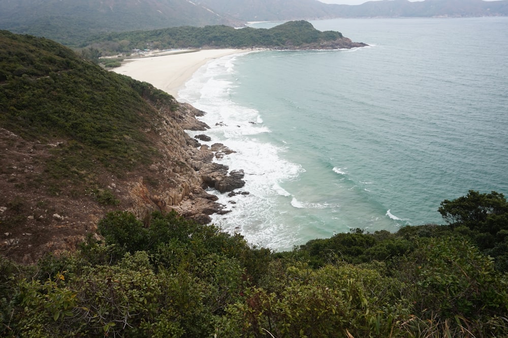 green and brown mountain beside body of water during daytime