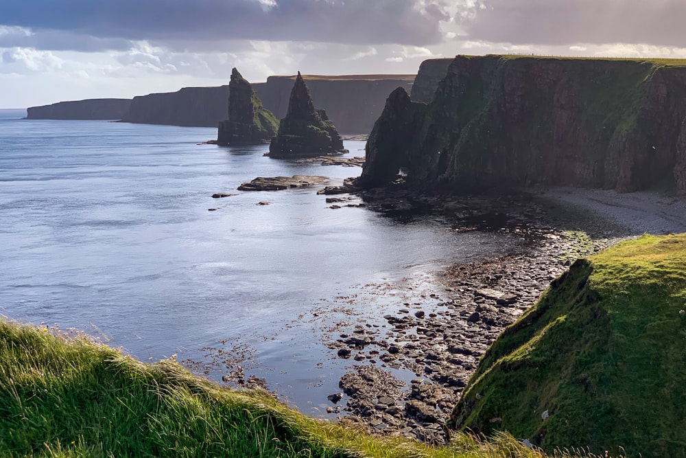 green and brown rock formation on sea during daytime