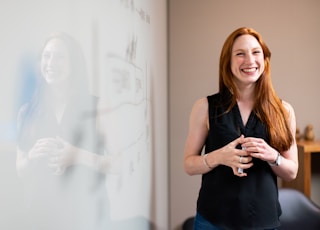 woman in blue tank top standing beside white wall