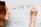 A person is writing on a whiteboard using a black marker. The words 'USE APIs' and 'FEEDBACK' are visible. The individual has red hair and is wearing a bracelet.