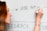 A person is writing on a whiteboard using a black marker. The words 'USE APIs' and 'FEEDBACK' are visible. The individual has red hair and is wearing a bracelet.