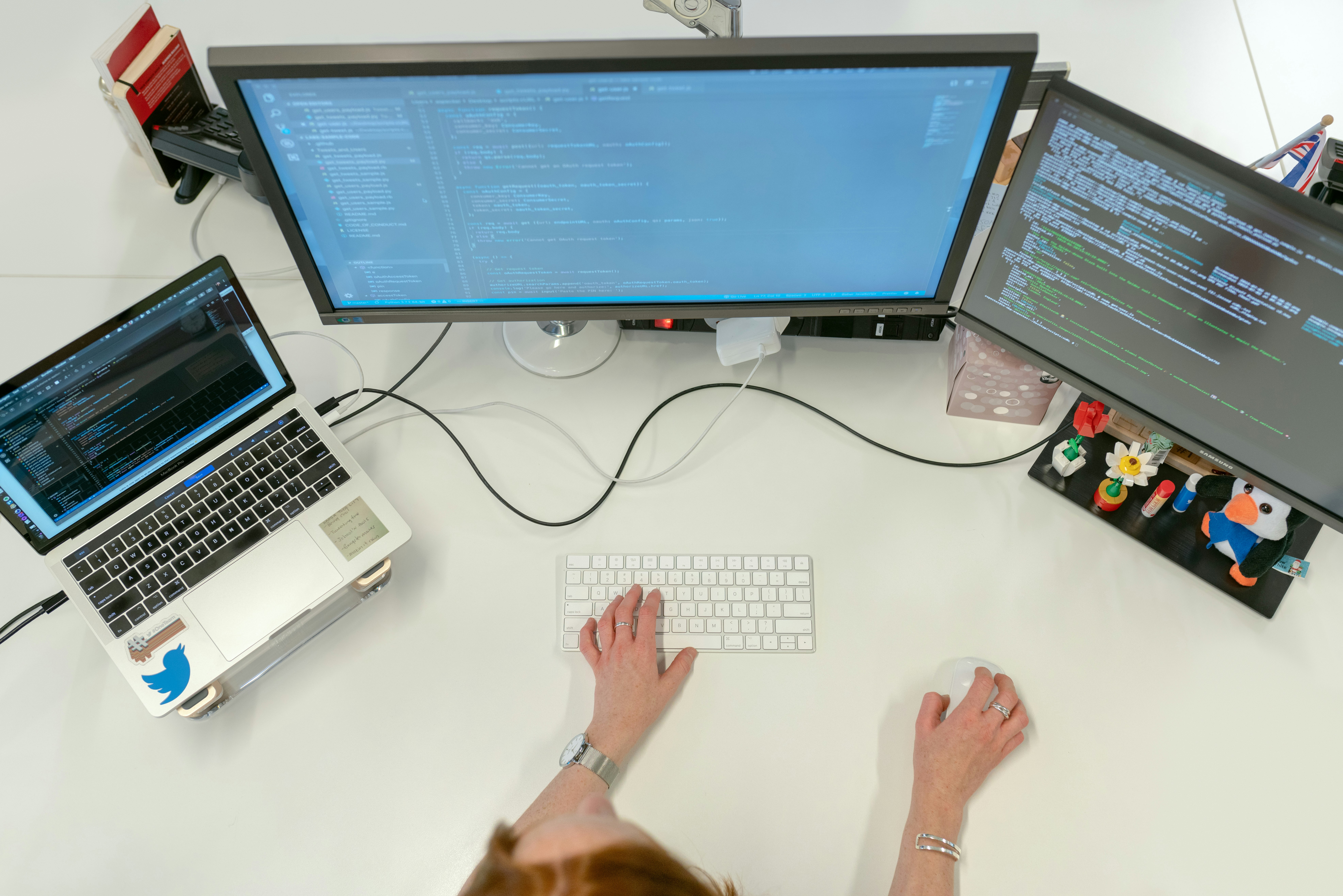 Female software engineer codes at her desk with computers