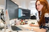woman in green shirt sitting in front of computer