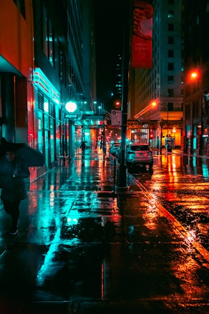street photography,how to photograph rain of colors; a person walking down a street holding an umbrella
