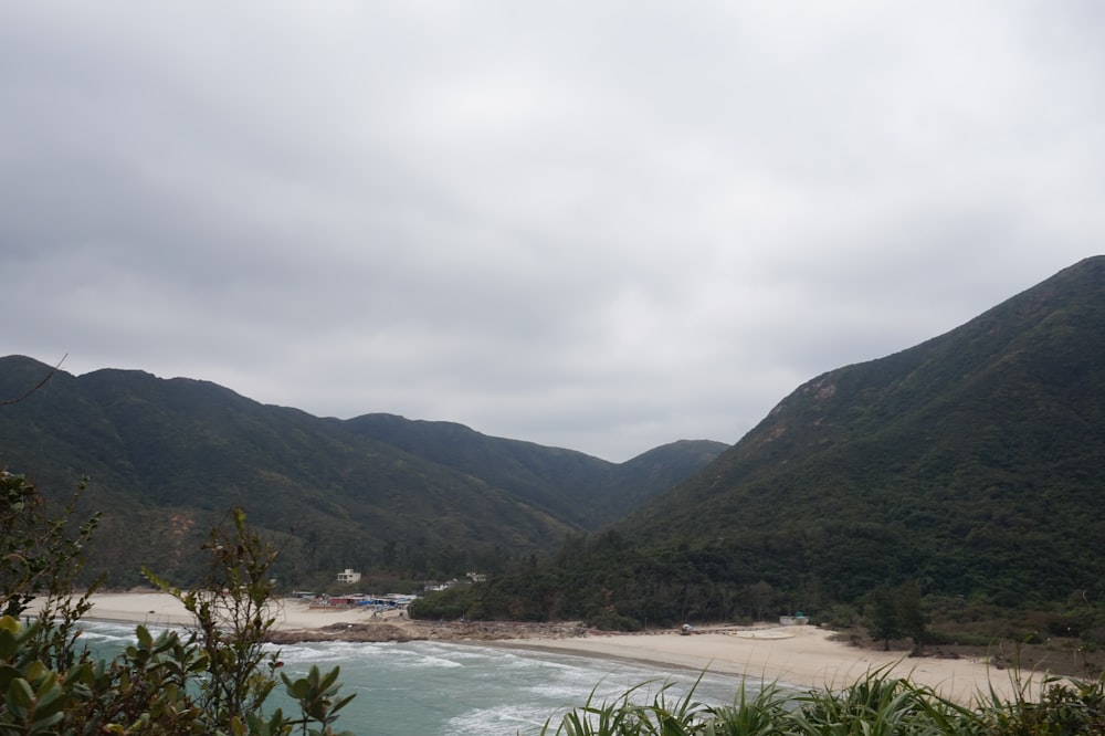 green mountains beside body of water under cloudy sky during daytime