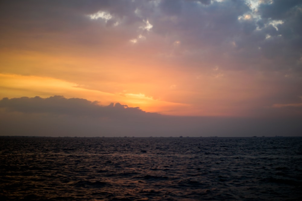 Cuerpo de agua bajo cielo nublado durante la puesta del sol
