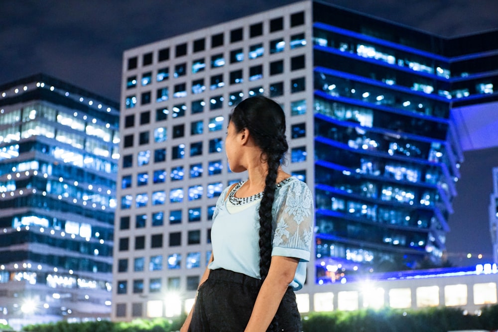 woman in white and black t-shirt standing near building during night time