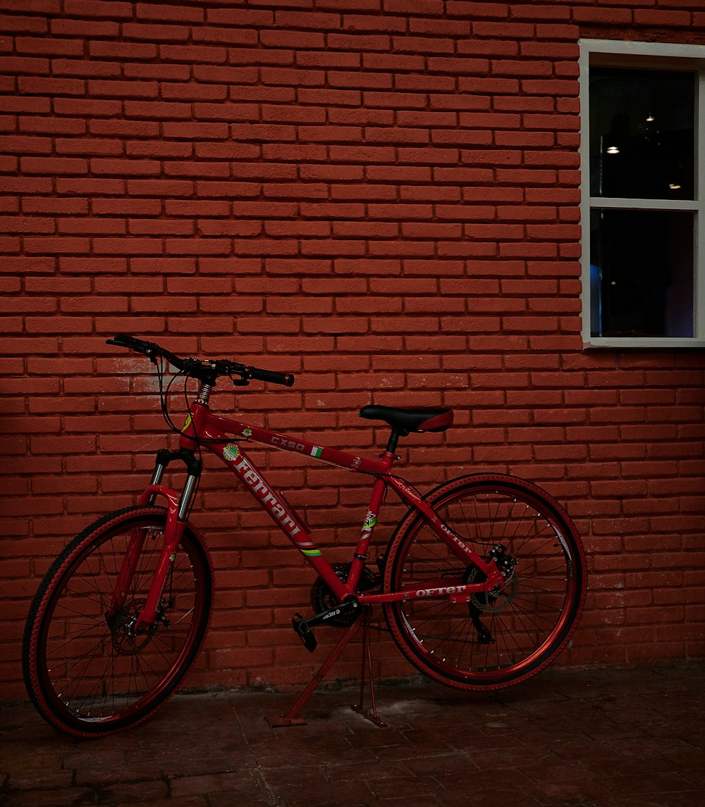 red and black road bike beside brown brick wall
