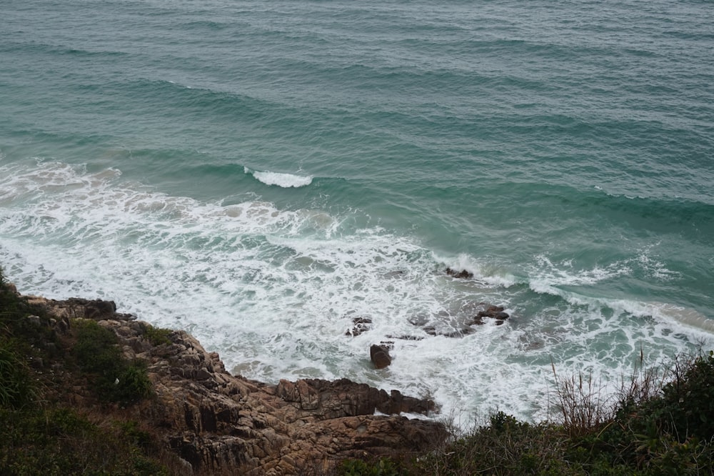 ocean waves crashing on brown rocky shore during daytime