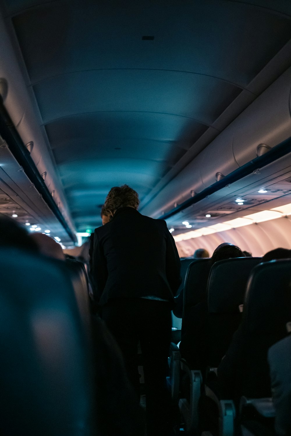 man in black jacket sitting on blue seat