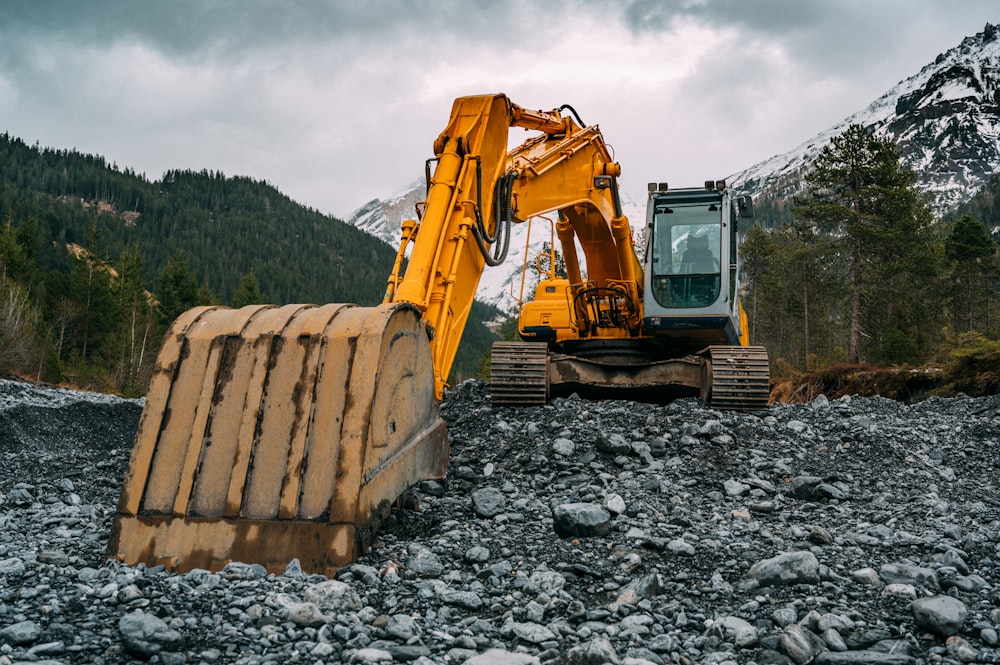 yellow and black excavator on rocky ground