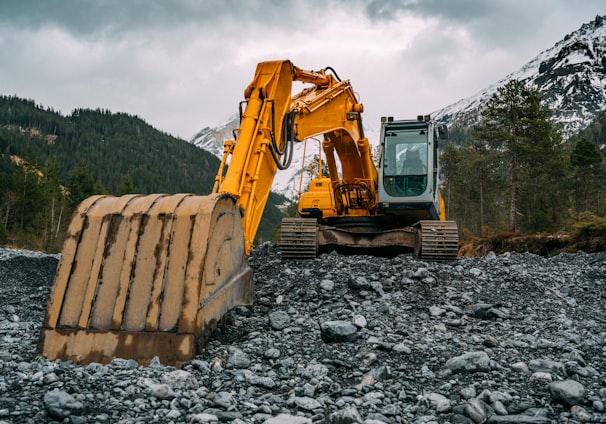 yellow and black excavator on rocky ground