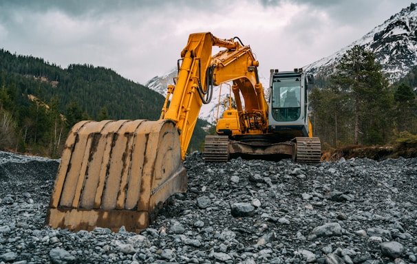 yellow and black excavator on rocky ground