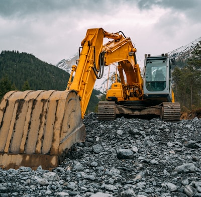 yellow and black excavator on rocky ground