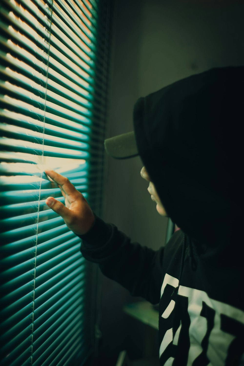 person in black long sleeve shirt holding white window blinds