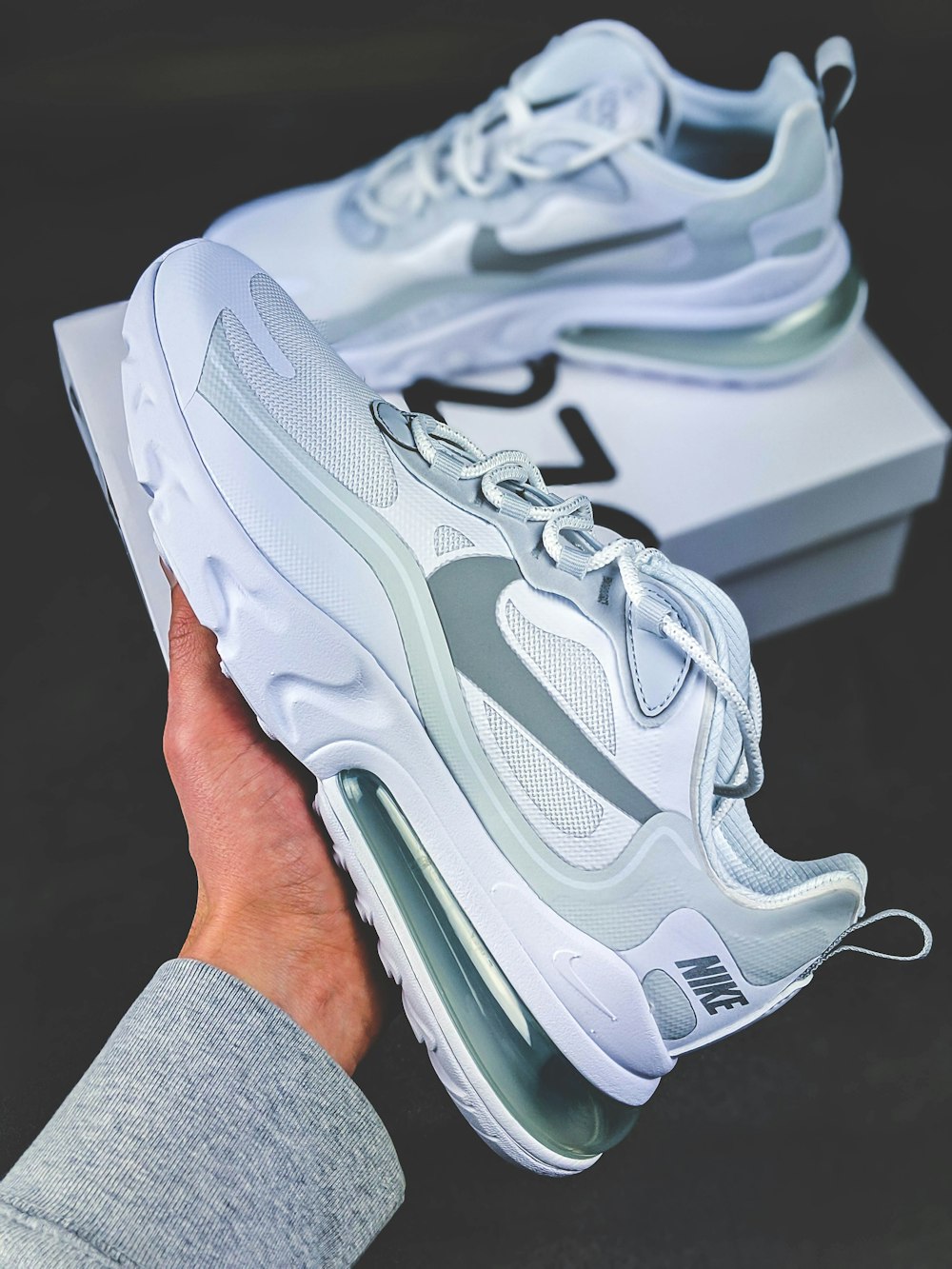 person holding gray and white nike air max