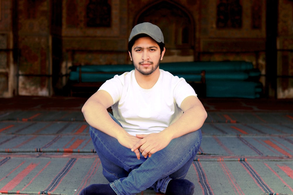 man in white crew neck t-shirt and blue denim jeans sitting on red and white