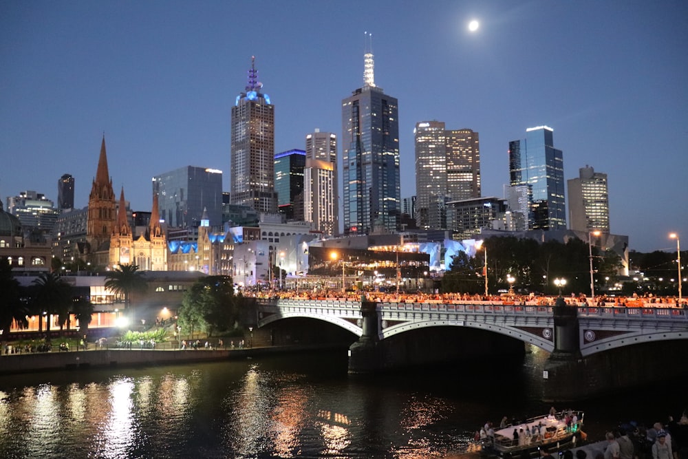 bridge over river near city buildings during night time