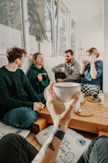 people sitting on chair holding white ceramic mug