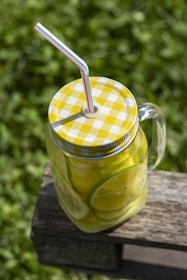 Bright yellow misket limonu fruits alongside a glass jar filled with limon özü.