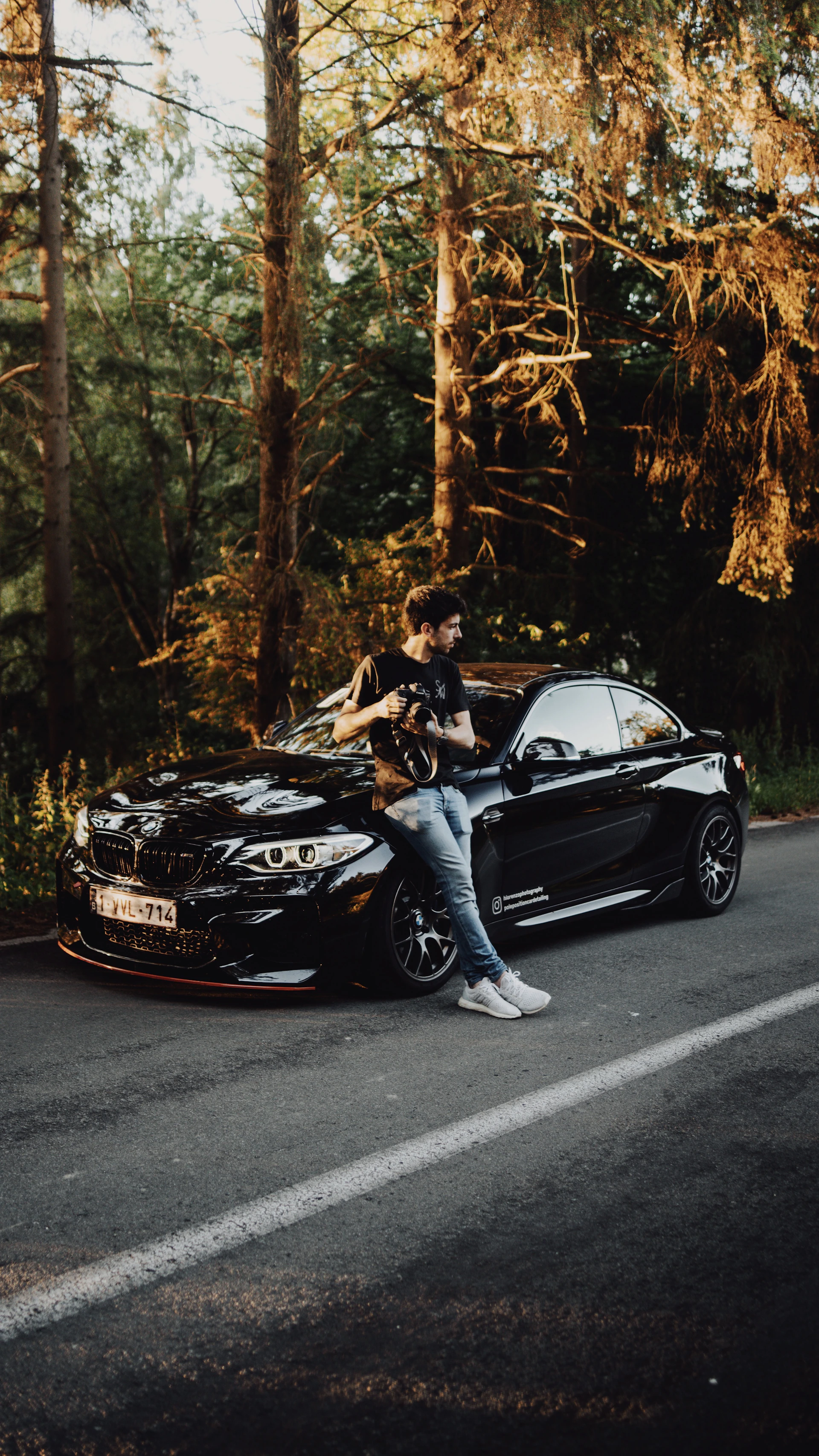 man and woman sitting on black mercedes benz coupe on road during daytime