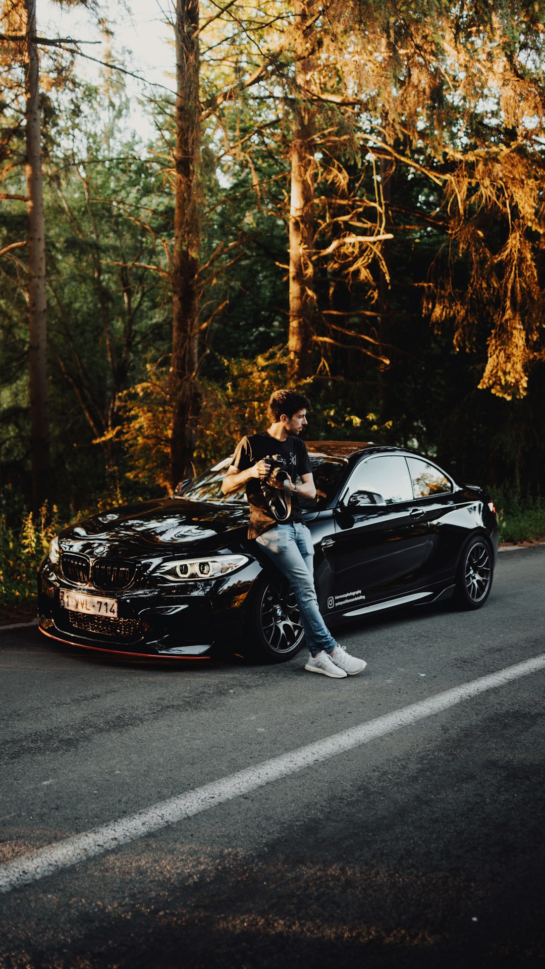 man and woman sitting on black mercedes benz coupe on road during daytime