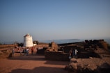 Tourists exploring a historic lighthouse on a clear, sunny day.