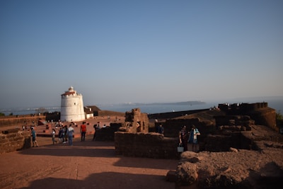 Tourists exploring a historic lighthouse on a clear, sunny day.