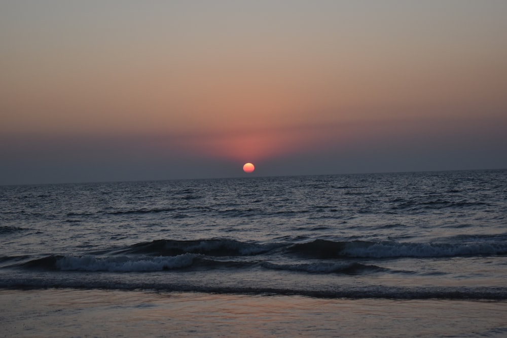 ocean waves crashing on shore during sunset